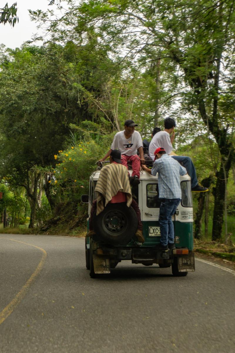 A public transport Jeep with men sitting on the roof and back of the Jeep
