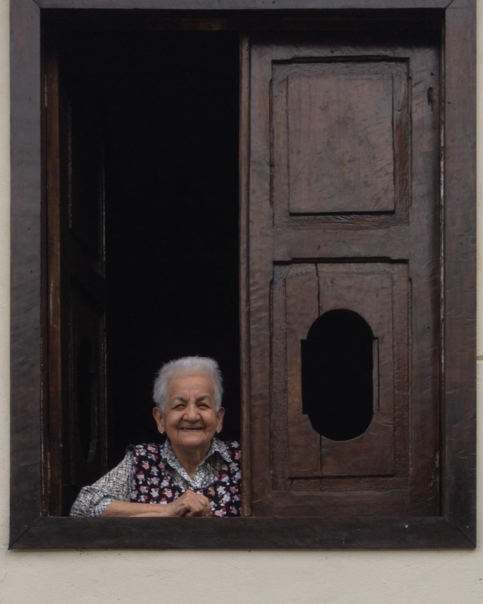 Mujer de corto cabello blanco asomándose por la ventana de una casa en Fredonia. Mujer de corto cabello blanco asomándose por la ventana de una casa en Fredonia.