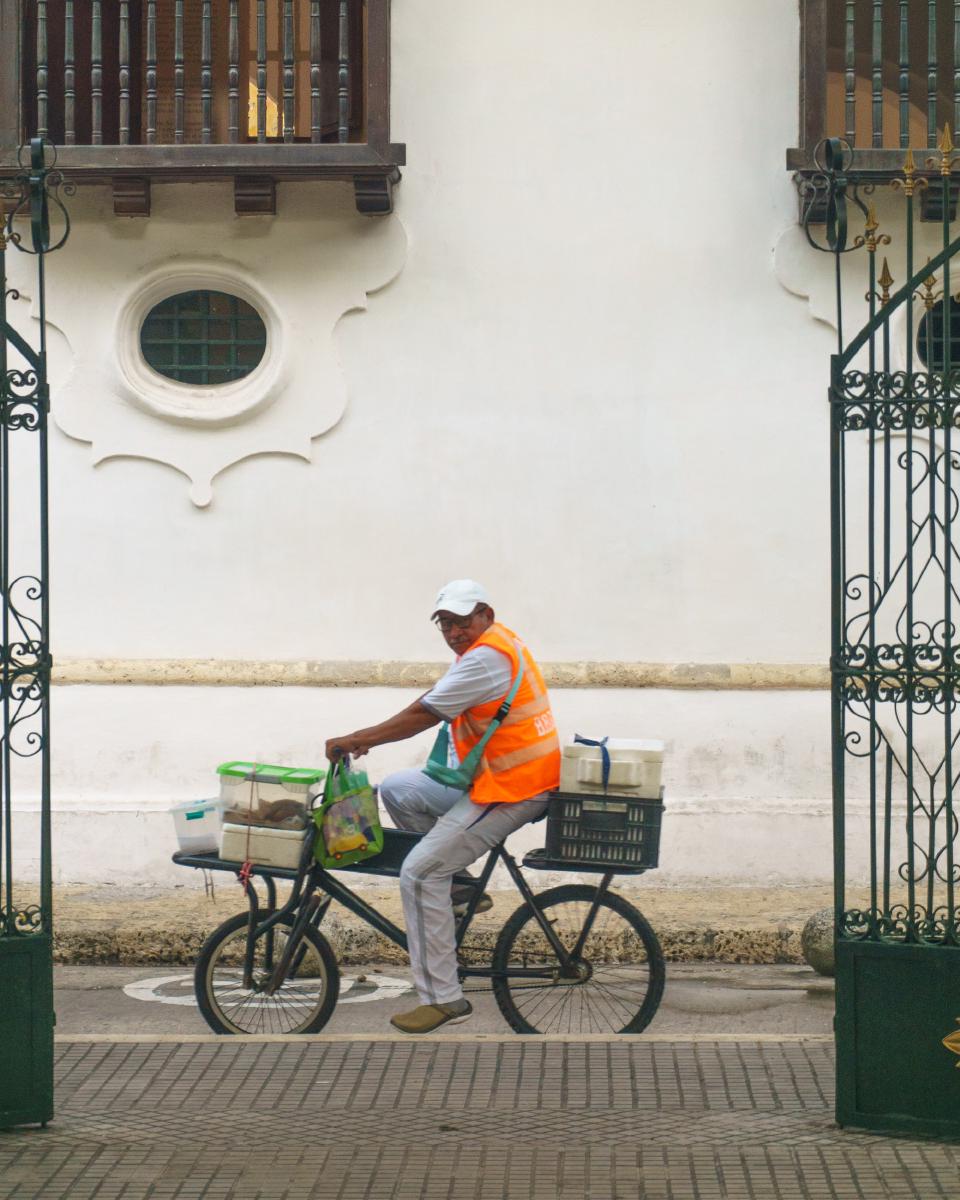 Vendedor montado en su bicicleta, cruzando la Plaza de Bolívar frente al Palacio de la Inquisición