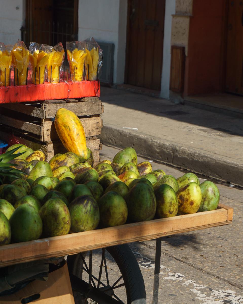 Puesto callejero de madera, de venta de frutas, mango, mango pelado y papaya