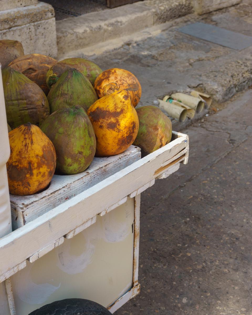 Puesto callejero de madera pintada de blanco, exhibiendo cocos a la venta en el centro de Cartagena