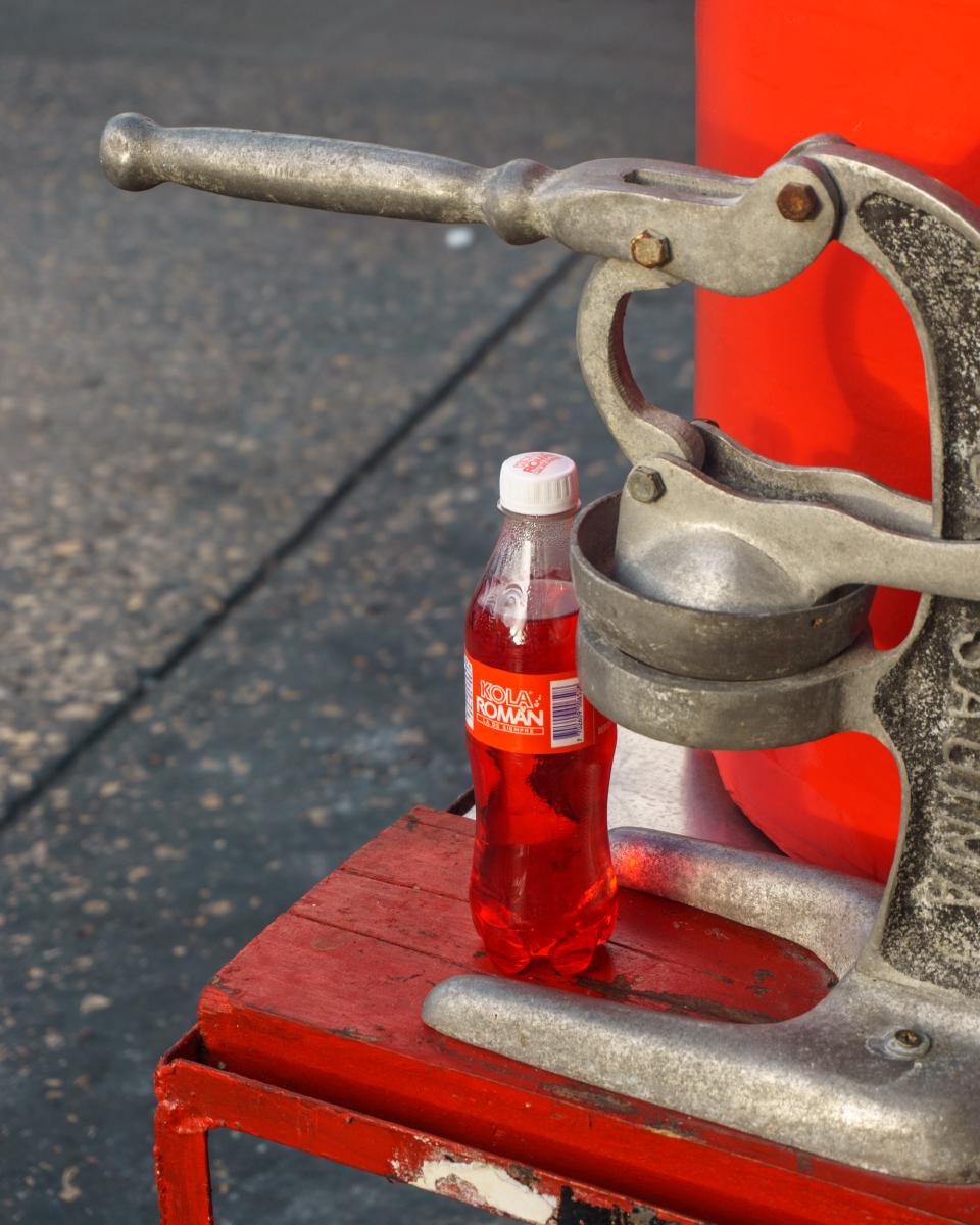 Puesto de bebidas en la calle con una botella de Kola Román