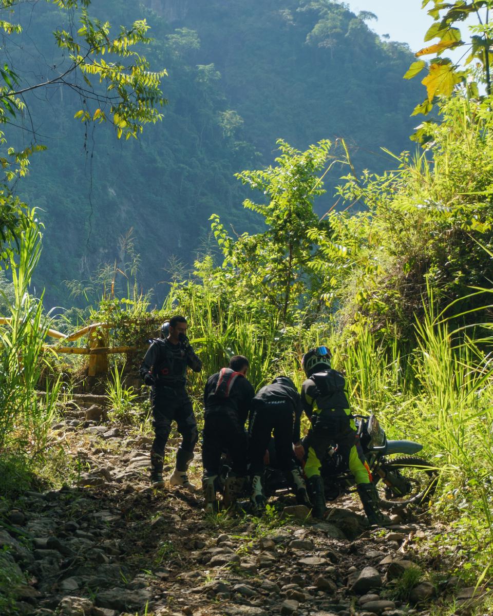 Motocrosistas levantando una moto