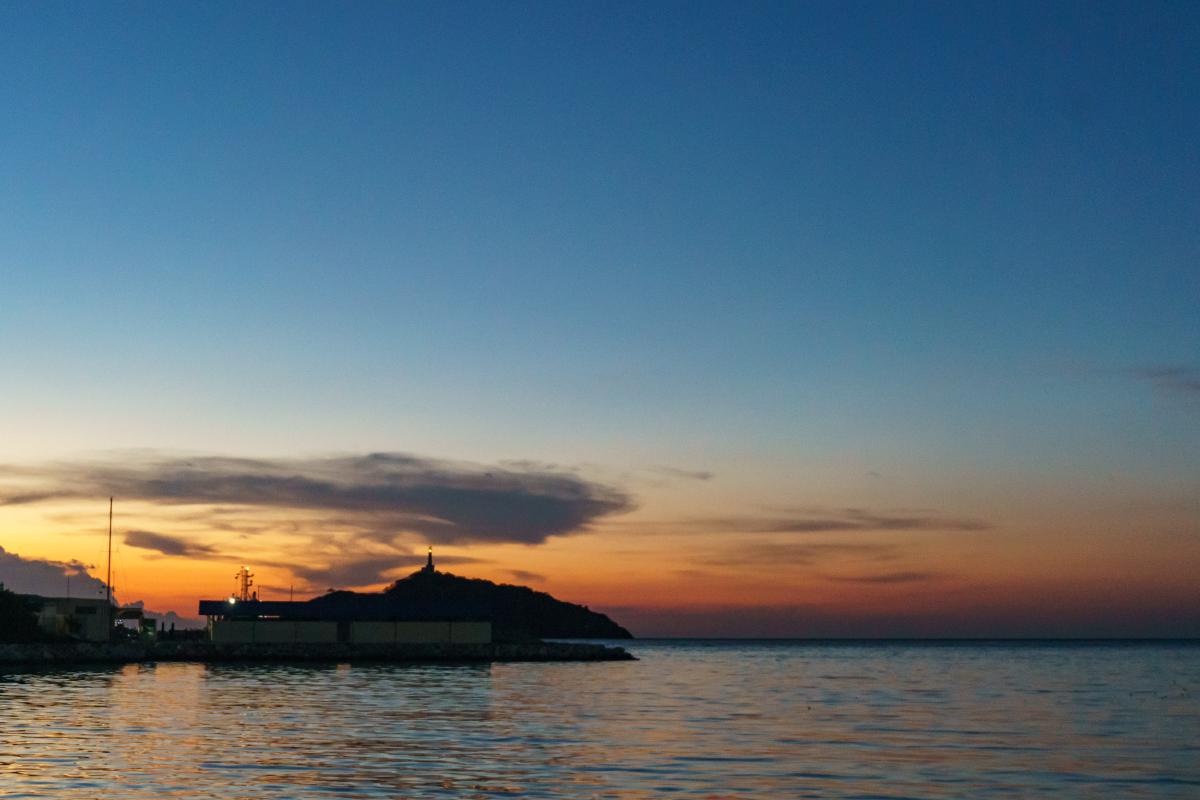 Atardecer desde El Camellón con vista al mar, el faro y el cielo naranja